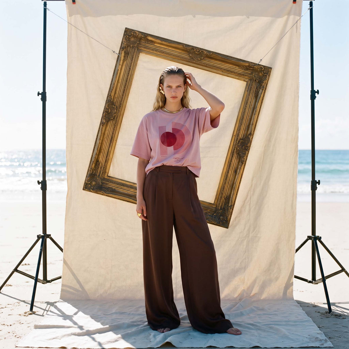 Full-length view of the blush AYLA organic cotton boxy tee styled beside a gilt frame – Oldest Daughter, Byron Bay